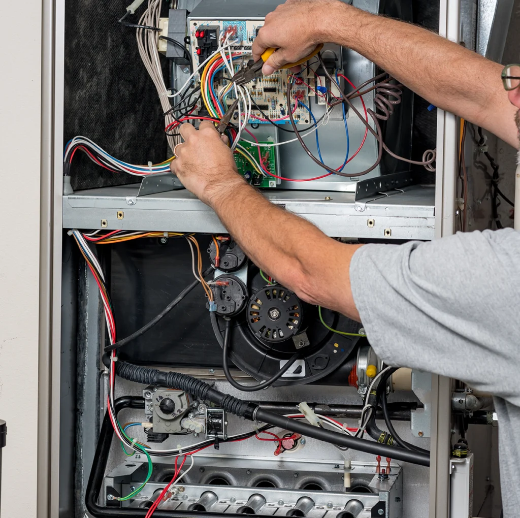 Technician inspecting a furnace for a cracked heat exchanger and other safety issues.